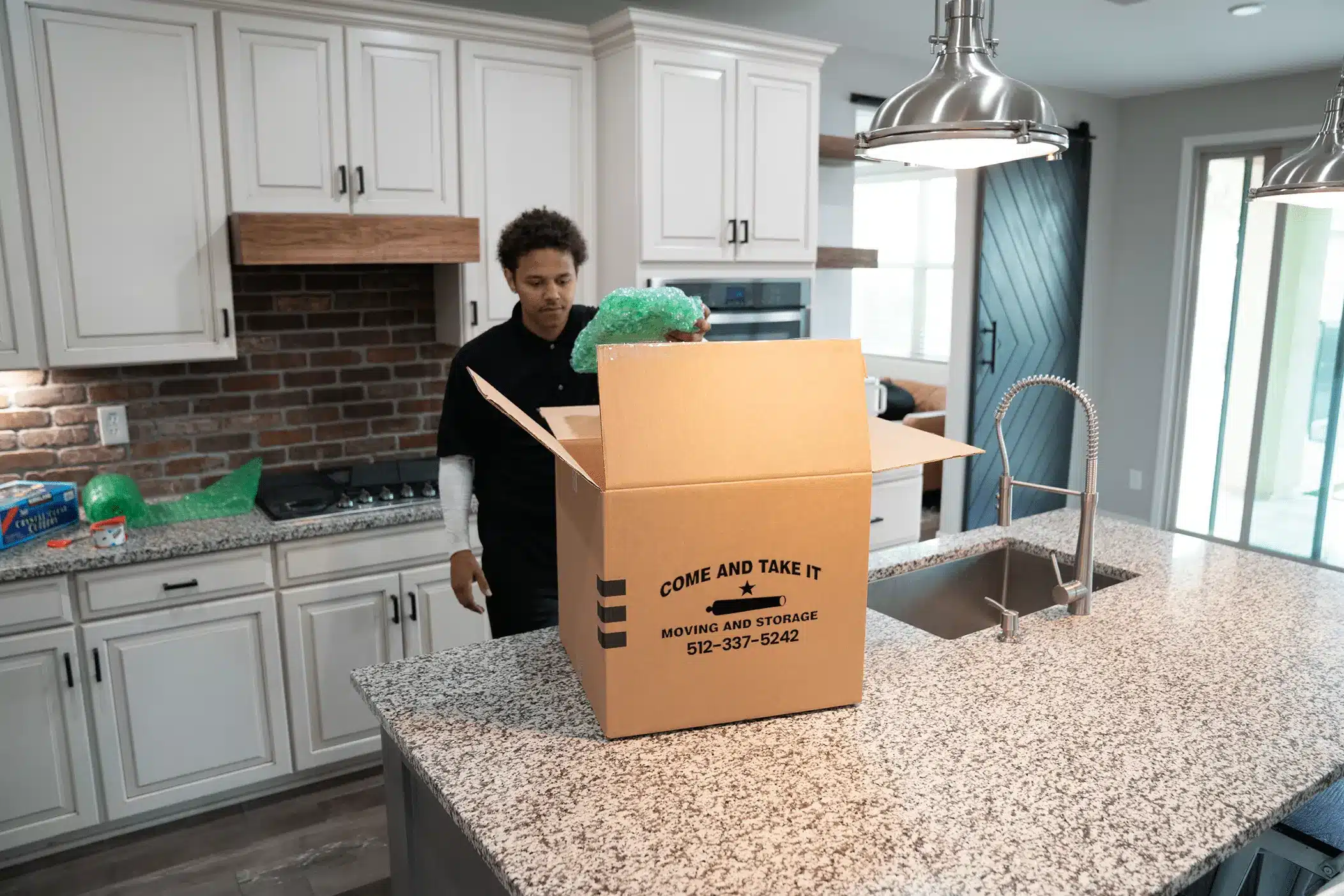 a member of Come and Take It Moving in a kitchen ready to move a box